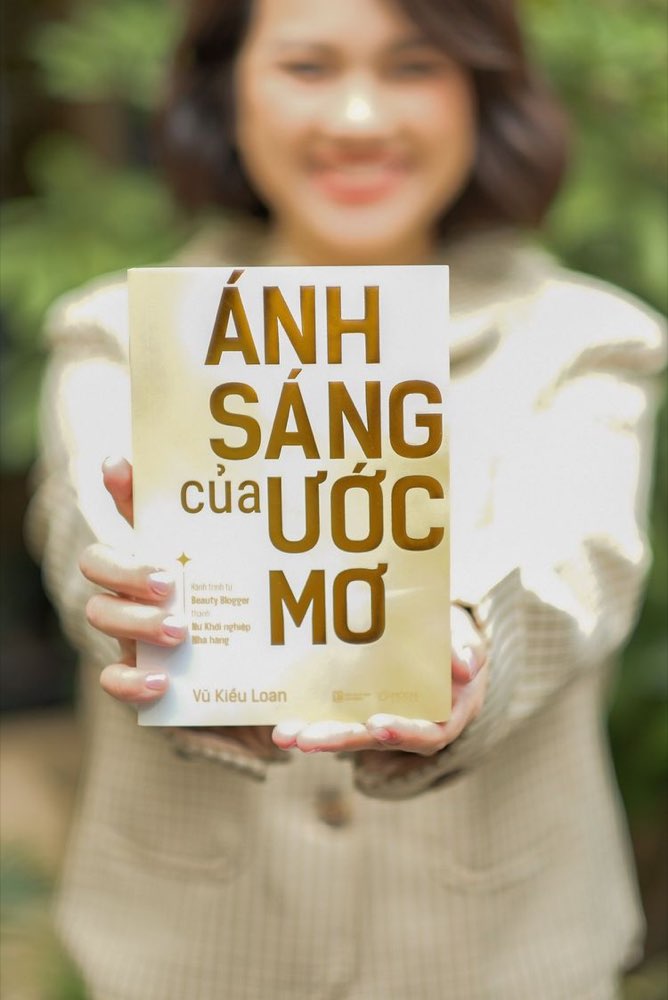 Vũ Kiều Loan cầm cuốn tự truyện Ánh Sáng Của Ước Mơ trên tay